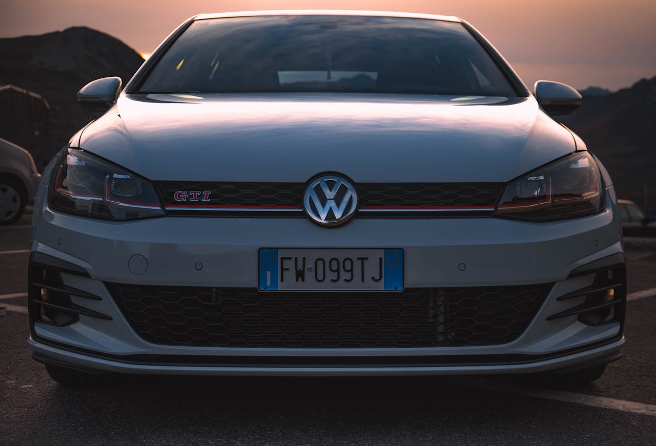 Front view of a Volkswagen Golf GTI parked outdoors at sunset showcasing its sleek design.