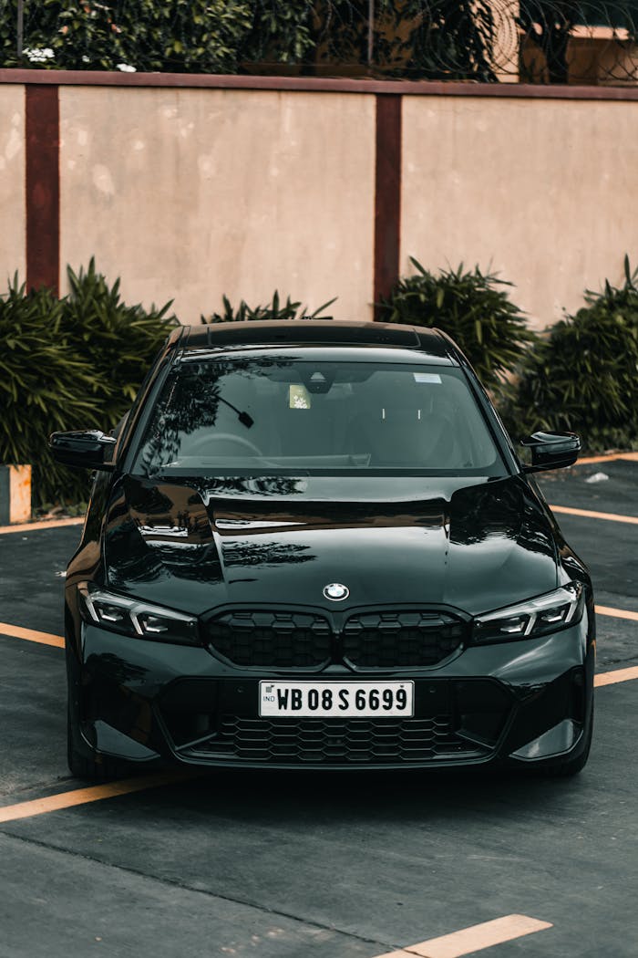 A sleek black BMW parked in an outdoor setting with lush greenery.